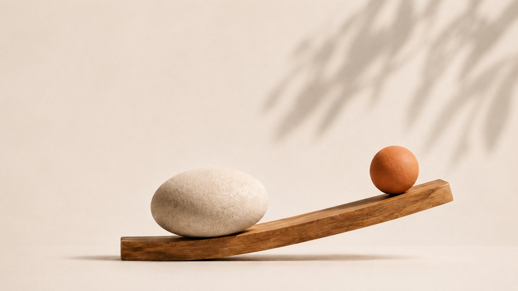 Una piedra y una esfera de terracota en equilibrio sobre una tabla de madera